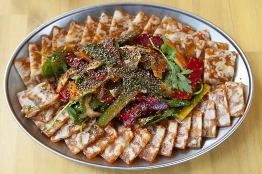 둥근 접시에 돌려 담은 닭발편육과 채소 무침, 깨 고명
