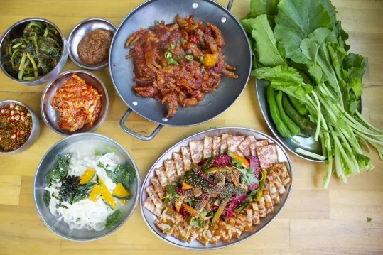 위에서 본 한 상 — 닭발 팬, 닭발편육 접시, 국수 그릇, 반찬, 쌈채소와 풋고추